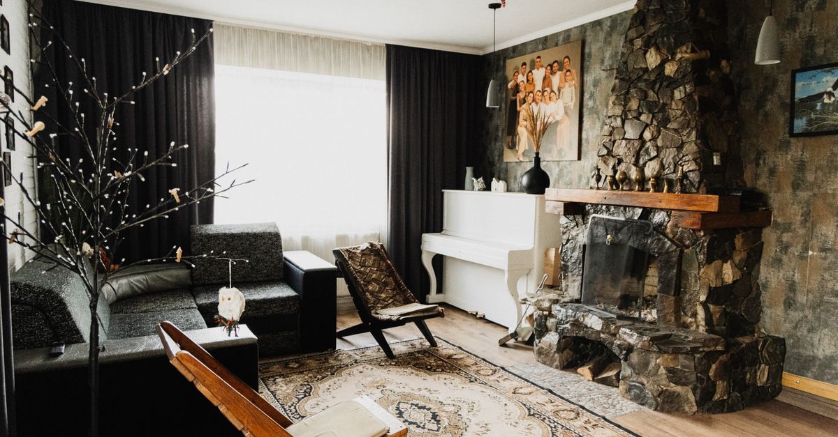 Warm and inviting living room featuring a stone fireplace, a white piano, and comfortable seating arrangements.