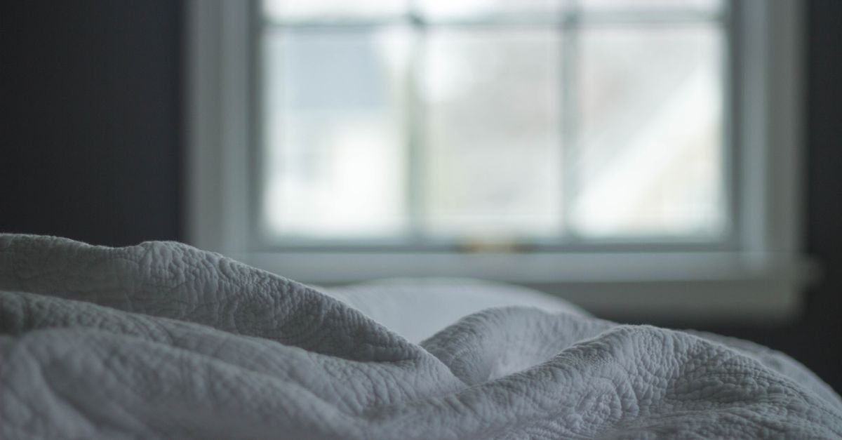A tranquil bedroom view with a quilted blanket by the window softly lit by morning light, ideal for relaxation themes.