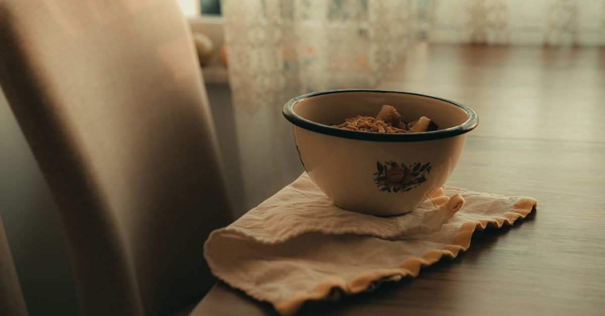 A vintage bowl filled with breakfast cereal on a table in warm sunlight.