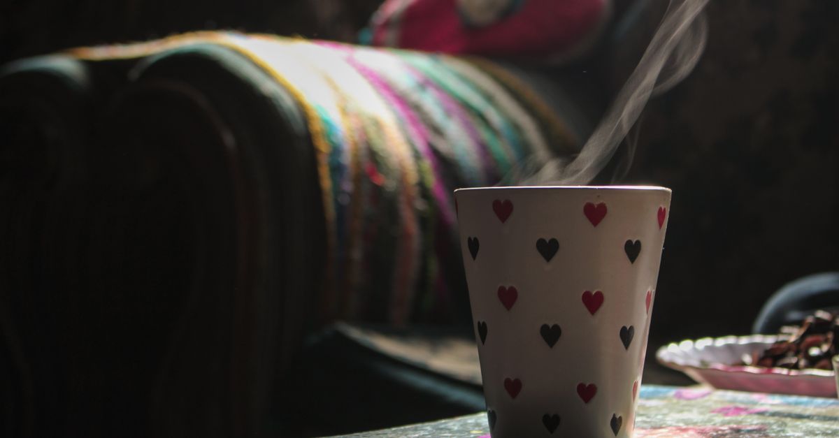A heart-patterned coffee mug releasing steam in a cozy indoor setting, creating a warm atmosphere.
