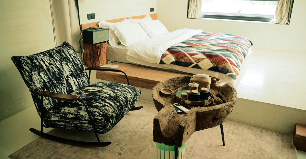 Inviting minimalist bedroom featuring a cozy bed, stylish rocking chair, and unique wooden table.